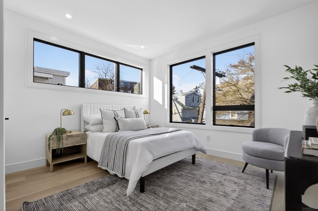 Bright bedroom with corner windows and a sitting chair